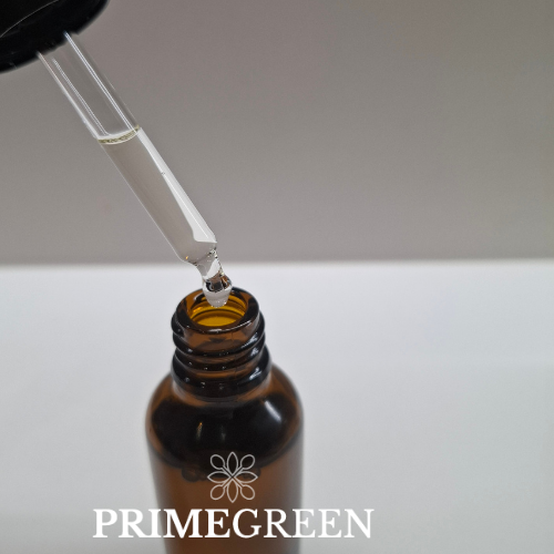 Brown glass bottle with babassu oil inside a dropper labeled 'Primegreen' on a neutral background