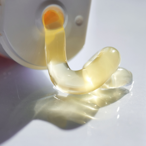 Close-up of a yellowish gel-like substance being dispensed from a container.